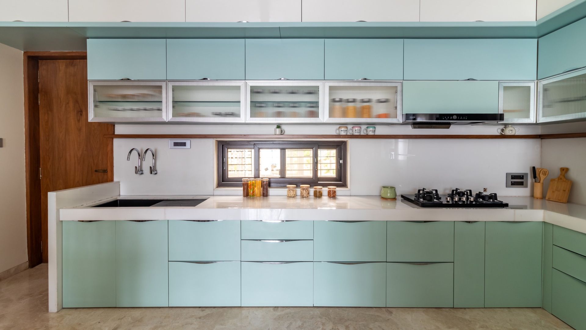 Mint-green modular kitchen with frosted-glass uppers and a stone counter — Chandradev, Parner