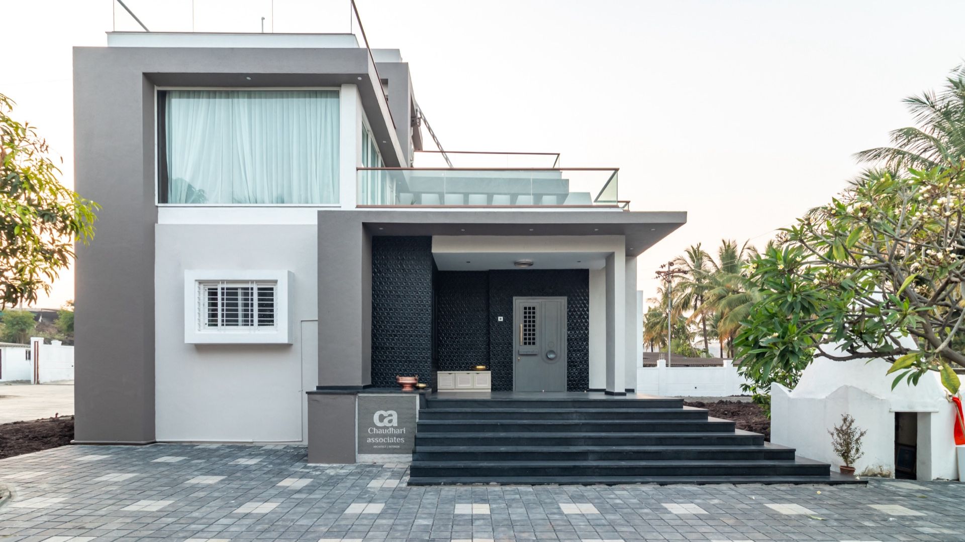 White-and-charcoal contemporary farmhouse façade with a wide stone stair — Karandi