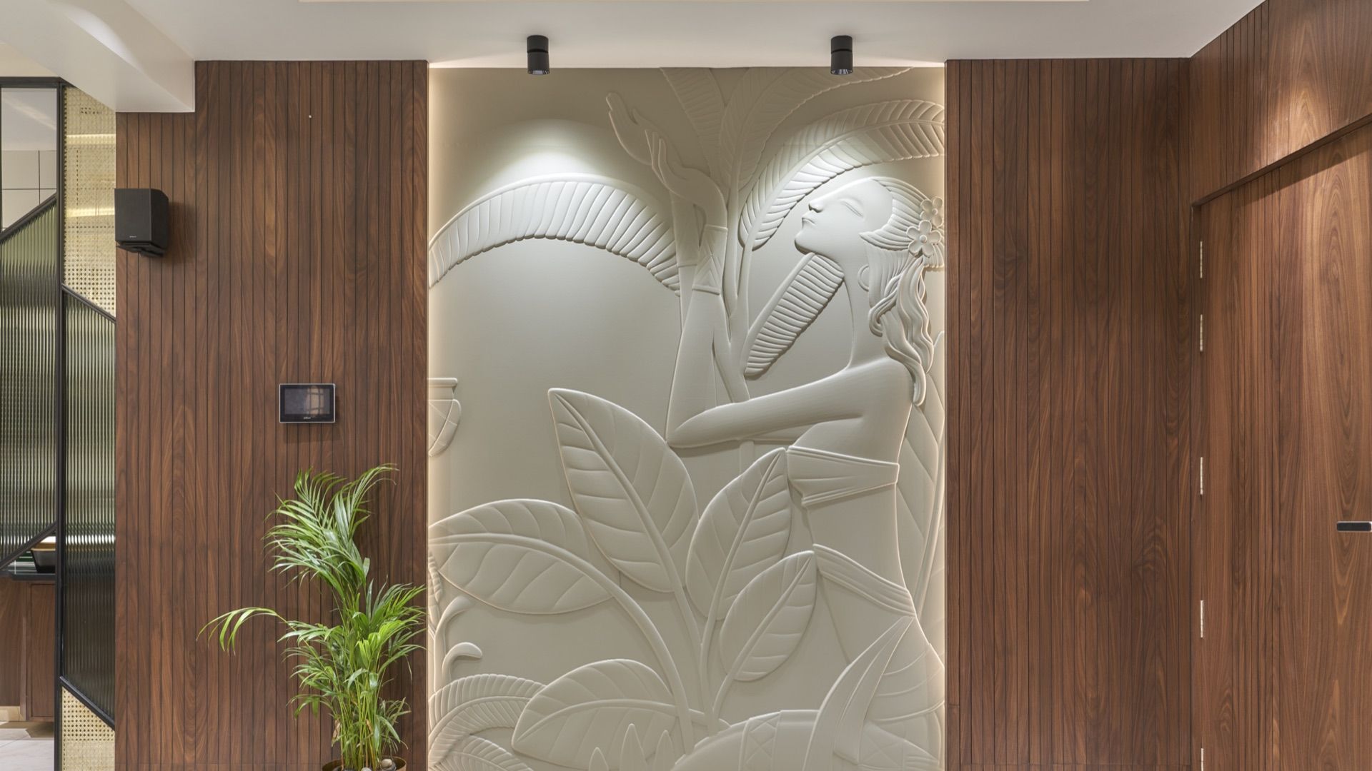 Entrance wall carved with a tropical relief between walnut panels — Shreenivas